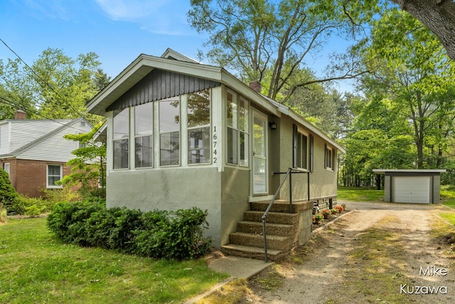 16742 148th Ave, Spring Lake, MI 49456 - view of front of property featuring driveway, an outbuilding, stucco siding, a garage, and a chimney