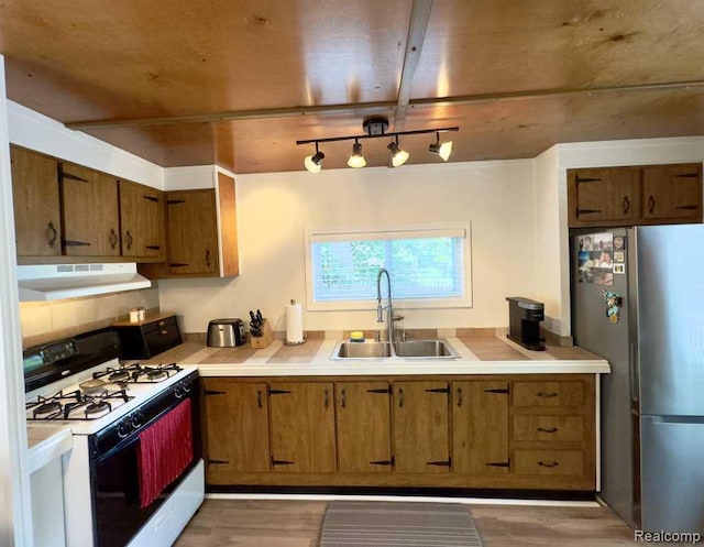 3840 Beech St, Burtchville, MI 48059 - kitchen with gas range, freestanding refrigerator, under cabinet range hood, light countertops, and light wood-type flooring