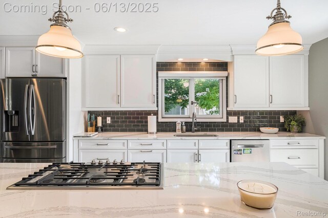 16039 Knobhill Dr, Argentine, MI 48451 - kitchen with stainless steel appliances, a sink, white cabinetry, pendant lighting, and tasteful backsplash