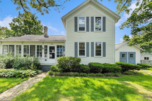 1111 W Park St, Lapeer, MI 48446 - view of front of home with a sunroom, a front yard, a chimney, and a shingled roof