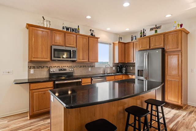 1754 Hightree Dr SW, Byron Center, MI 49315 - kitchen featuring stainless steel appliances, light wood-style floors, a kitchen bar, dark countertops, and recessed lighting