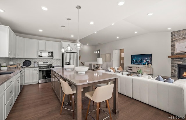 16136 Conifer Ln, Clinton Township, MI 48038 - kitchen featuring stainless steel appliances, open floor plan, decorative backsplash, a kitchen island, and vaulted ceiling
