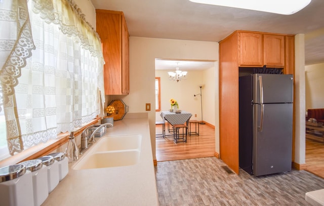 402 Division St, Union City, MI 49094 - kitchen with freestanding refrigerator, a sink, light wood-style floors, a chandelier, and light countertops