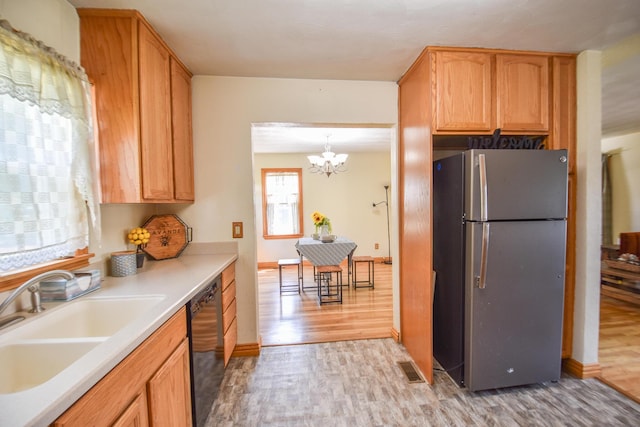 402 Division St, Union City, MI 49094 - kitchen featuring freestanding refrigerator, a sink, dishwasher, light wood-style floors, and a chandelier