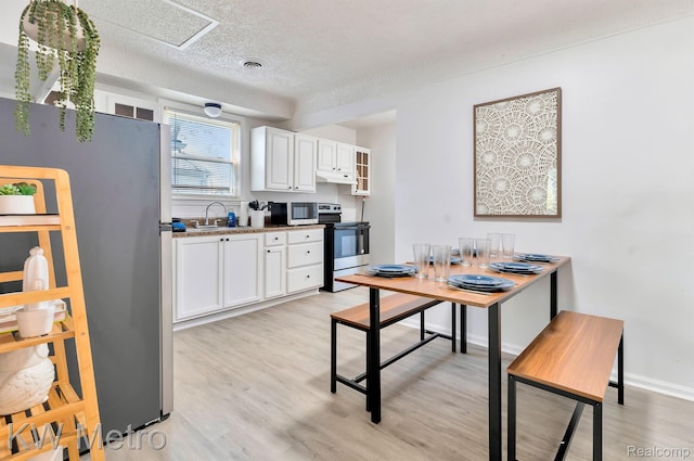 19391 Inkster Rd, Livonia, MI 48152 - kitchen featuring appliances with stainless steel finishes, white cabinets, light wood-style flooring, under cabinet range hood, and a textured ceiling