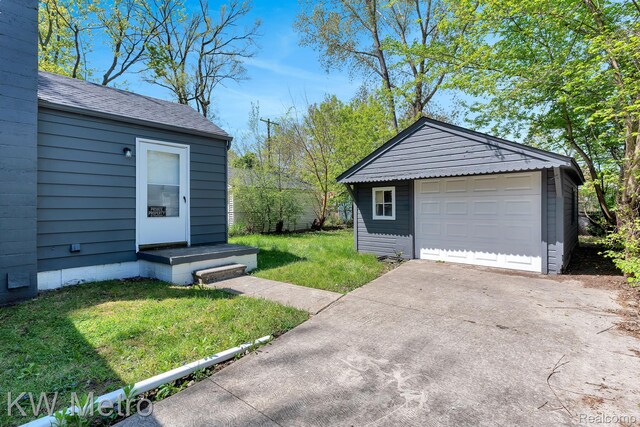 19391 Inkster Rd, Livonia, MI 48152 - view of grassy yard with driveway, a detached garage, and an outbuilding