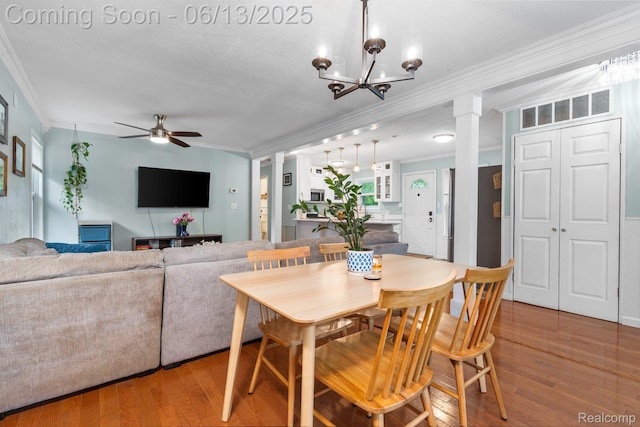 3341 Creek Dr, Ann Arbor, MI 48108 - dining area featuring ornamental molding, ceiling fan, wood finished floors, decorative columns, and a chandelier