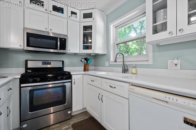 3341 Creek Dr, Ann Arbor, MI 48108 - kitchen with appliances with stainless steel finishes, light countertops, white cabinetry, ornamental molding, and glass insert cabinets