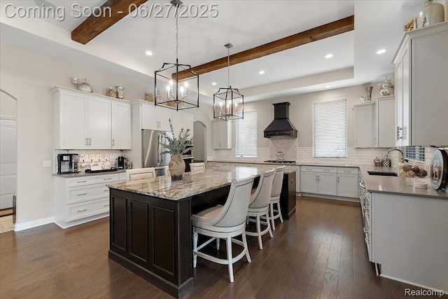 3610 Piccadilly Dr, Rochester Hills, MI 48309 - kitchen with wall chimney exhaust hood, appliances with stainless steel finishes, a kitchen island, beamed ceiling, and arched walkways