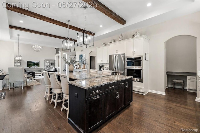 3610 Piccadilly Dr, Rochester Hills, MI 48309 - kitchen with stainless steel appliances, arched walkways, dark cabinetry, beam ceiling, and dark wood-style flooring