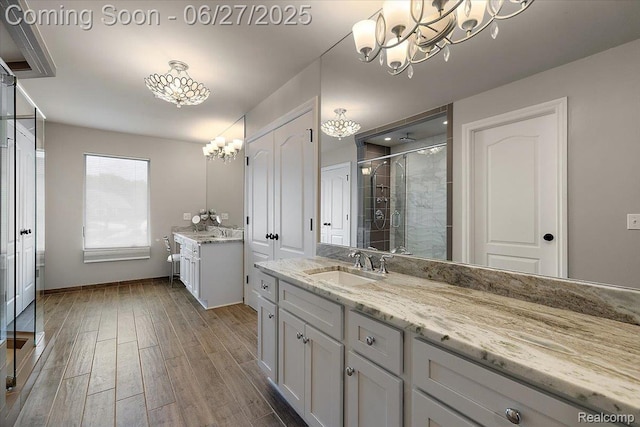 3610 Piccadilly Dr, Rochester Hills, MI 48309 - bathroom featuring a chandelier, a shower stall, two vanities, and wood finished floors