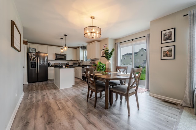 32822 Ravine St, New Haven, MI 48048 - dining area featuring light wood-type flooring, a chandelier, and baseboards