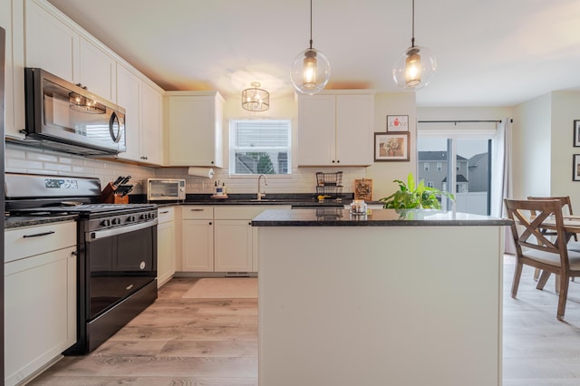 32822 Ravine St, New Haven, MI 48048 - kitchen with stainless steel microwave, gas range, light wood-type flooring, and decorative backsplash