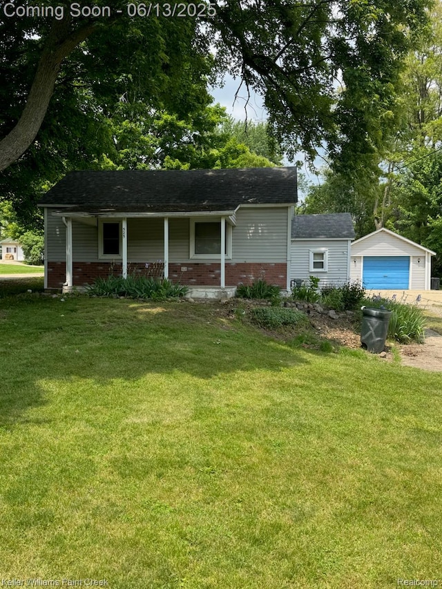 525 E Saint Clair St, Almont, MI 48003 - view of front of property with a porch, a front yard, brick siding, driveway, and a detached garage