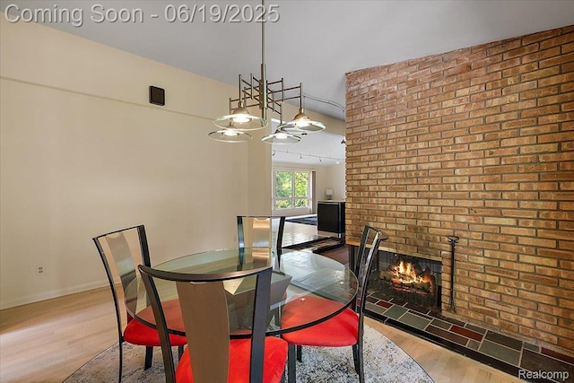 2732 Lone Pine Rd, West Bloomfield, MI 48323 - dining space featuring wood finished floors, brick wall, a fireplace, and a chandelier