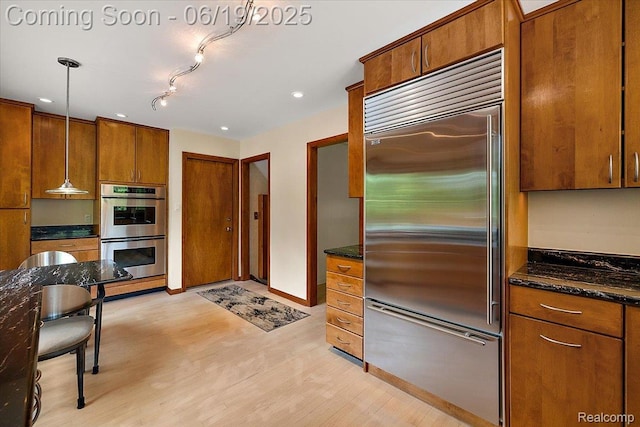 2732 Lone Pine Rd, West Bloomfield, MI 48323 - kitchen featuring stainless steel appliances, brown cabinetry, light wood-style floors, pendant lighting, and dark stone countertops