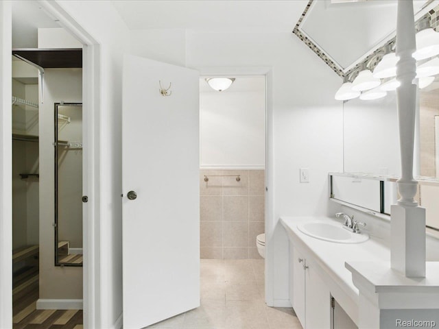 810 Holland Ave Unit 5, Port Huron, MI 48060 - bathroom with a spacious closet, vanity, tile walls, tile patterned floors, and wainscoting