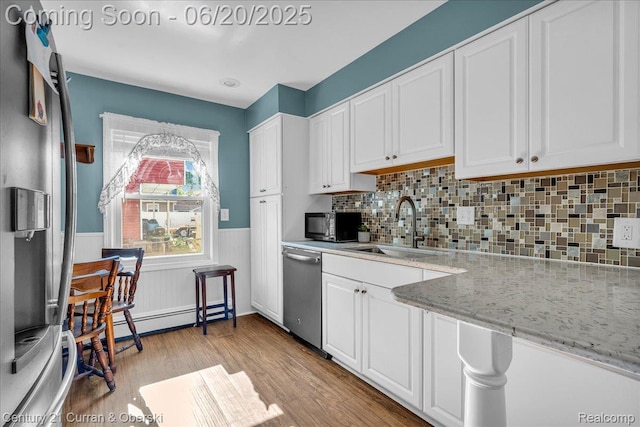 24121 Kraft Pl, Brownstown, MI 48174 - kitchen featuring appliances with stainless steel finishes, a wainscoted wall, white cabinets, and light wood-style flooring