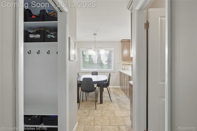 6821 Tamerlane Dr, West Bloomfield, MI 48322 - hallway with light stone finish flooring and a chandelier