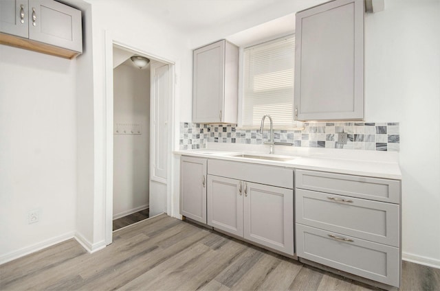 16086 Carlisle St, Detroit, MI 48205 - bathroom featuring a sink, wood finished floors, backsplash, and baseboards