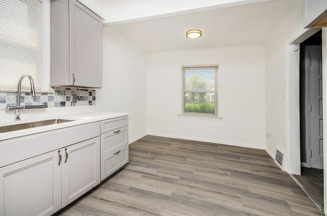 16086 Carlisle St, Detroit, MI 48205 - kitchen with a sink, decorative backsplash, light wood-style floors, light countertops, and baseboards