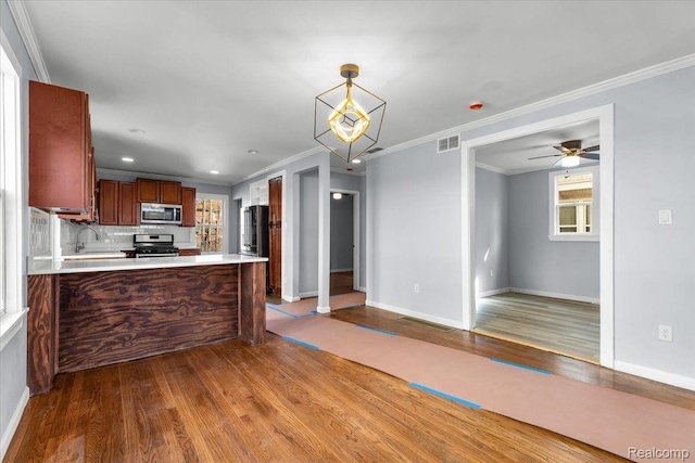 16558 Indiana St, Detroit, MI 48221 - kitchen with stainless steel appliances, wood finished floors, open floor plan, crown molding, and light countertops