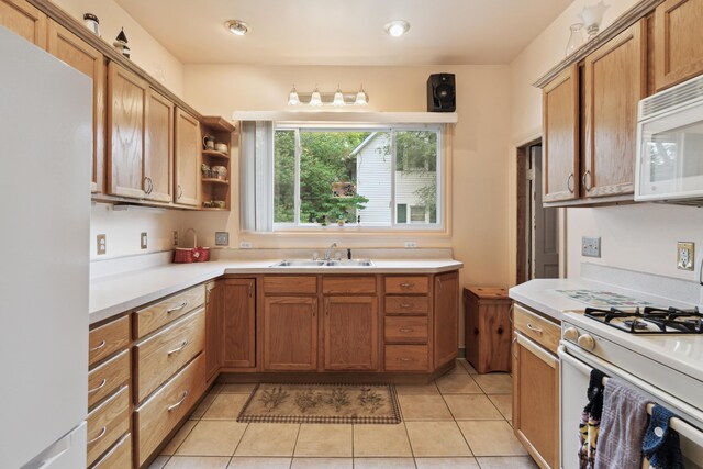 1704 Pringle Ave, Jackson, MI 49203 - kitchen featuring white appliances, a sink, light countertops, light tile patterned floors, and brown cabinetry
