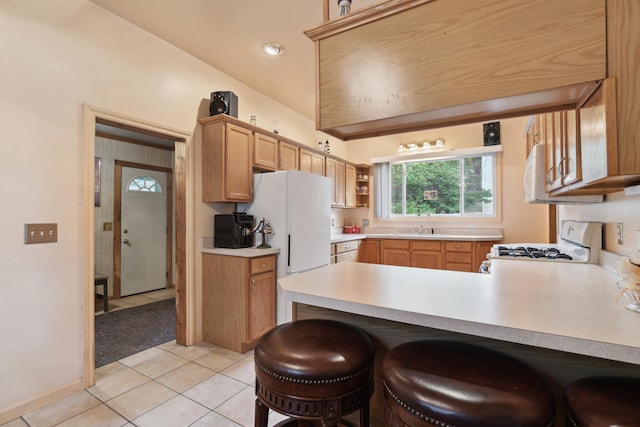 1704 Pringle Ave, Jackson, MI 49203 - kitchen featuring white range with gas cooktop, light tile patterned floors, light countertops, a peninsula, and a kitchen bar