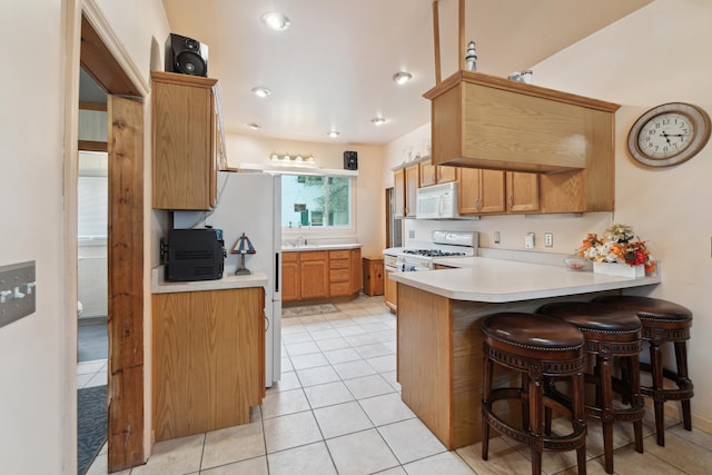 1704 Pringle Ave, Jackson, MI 49203 - kitchen featuring white appliances, a peninsula, light countertops, and light tile patterned floors
