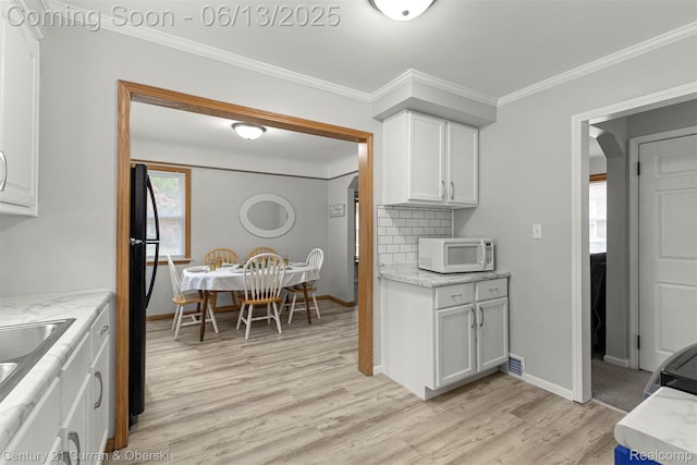 8904 Becker Ave, Allen Park, MI 48101 - kitchen featuring white microwave, light wood-style flooring, white cabinetry, ornamental molding, and freestanding refrigerator