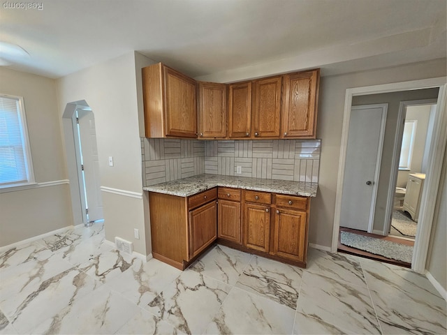 9311 Dixie, Redford, MI 48239 - kitchen featuring brown cabinets, arched walkways, light marble finish floors, and light stone countertops