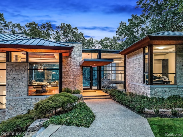 6956 Cooley Lake Rd, White Lake, MI 48383 - view of exterior entry featuring stone siding, a standing seam roof, and metal roof