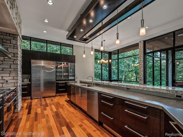 6956 Cooley Lake Rd, White Lake, MI 48383 - kitchen featuring premium appliances, a sink, modern cabinets, light wood-style flooring, and hanging light fixtures