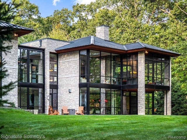 6956 Cooley Lake Rd, White Lake, MI 48383 - back of house featuring a sunroom, metal roof, a chimney, and stone siding