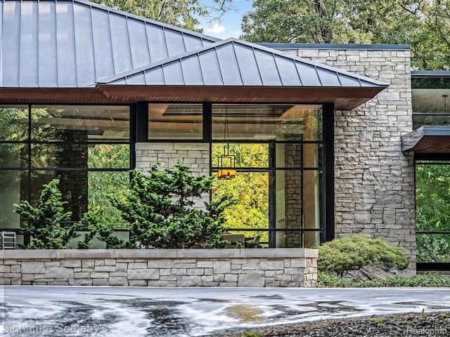 6956 Cooley Lake Rd, White Lake, MI 48383 - view of side of home with a standing seam roof, stone siding, and metal roof