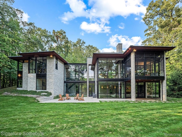 6956 Cooley Lake Rd, White Lake, MI 48383 - rear view of house featuring a sunroom, a patio, stone siding, and a lawn