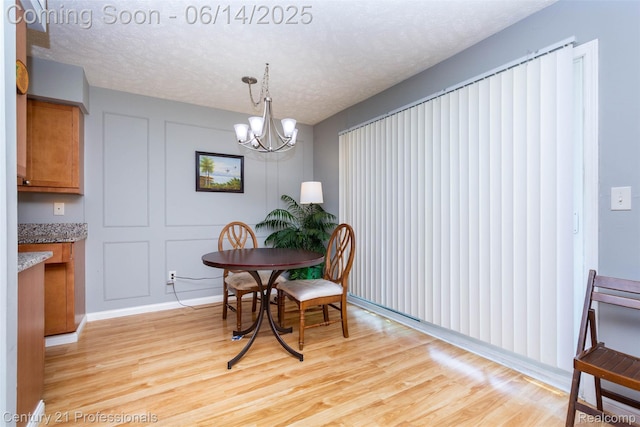 2024 Hamilton Rd Unit 6, Okemos, MI 48864 - dining area featuring light wood-style flooring, a chandelier, and a textured ceiling