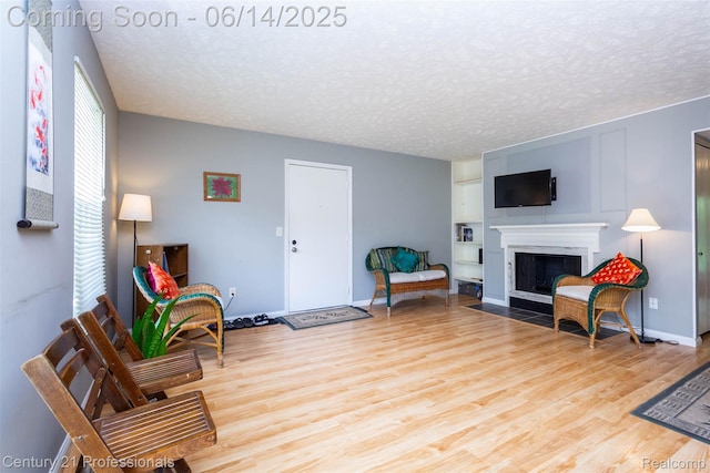 2024 Hamilton Rd Unit 6, Okemos, MI 48864 - living area featuring wood finished floors, a fireplace with flush hearth, a textured ceiling, and baseboards
