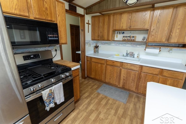 2312 Bay Ridge Dr, Au Gres, MI 48703 - kitchen featuring stainless steel gas stove, black microwave, a sink, light wood-style flooring, and brown cabinets