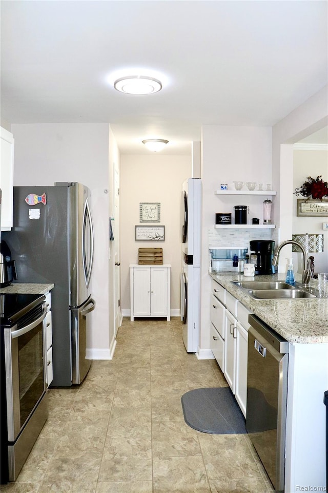 9418 Parkwood Dr N, Davison, MI 48423 - kitchen with stainless steel appliances, stacked washing machine and dryer, white cabinets, light stone countertops, and light tile patterned floors