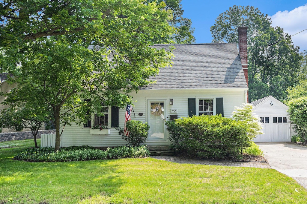 338 N Eagle St, Marshall, MI 49068 - cape cod home with an outbuilding, a garage, entry steps, a chimney, and a front yard