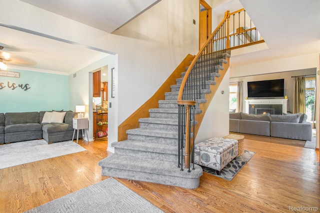 18704 Gary Ln, Livonia, MI 48152 - staircase featuring ceiling fan, wood finished floors, a lit fireplace, and ornamental molding