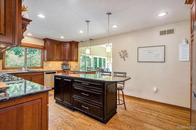 18704 Gary Ln, Livonia, MI 48152 - kitchen featuring stainless steel appliances, light wood finished floors, a breakfast bar, backsplash, and dark stone counters