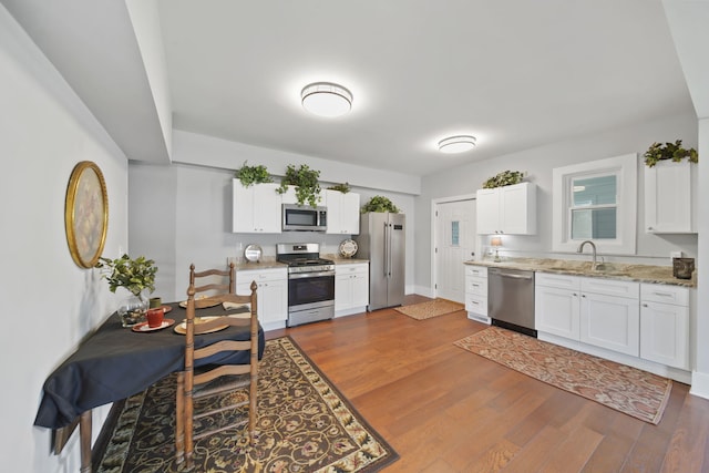 911 E Ganson St, Jackson, MI 49201 - kitchen with stainless steel appliances, a sink, dark wood-style flooring, white cabinetry, and light stone countertops