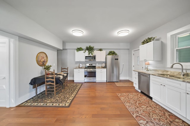 911 E Ganson St, Jackson, MI 49201 - kitchen featuring stainless steel appliances, a sink, white cabinetry, and light stone countertops