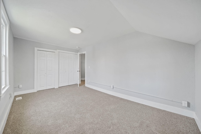 911 E Ganson St, Jackson, MI 49201 - unfurnished bedroom featuring two closets, carpet flooring, baseboards, and vaulted ceiling