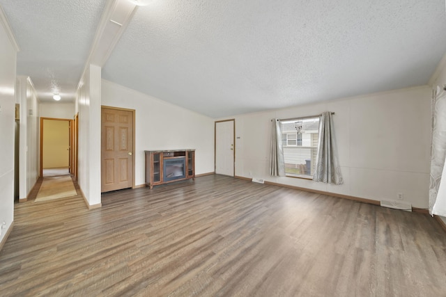 948 Savannah River Dr, Adrian, MI 49221 - unfurnished living room with a tiled fireplace, wood finished floors, a textured ceiling, baseboards, and lofted ceiling