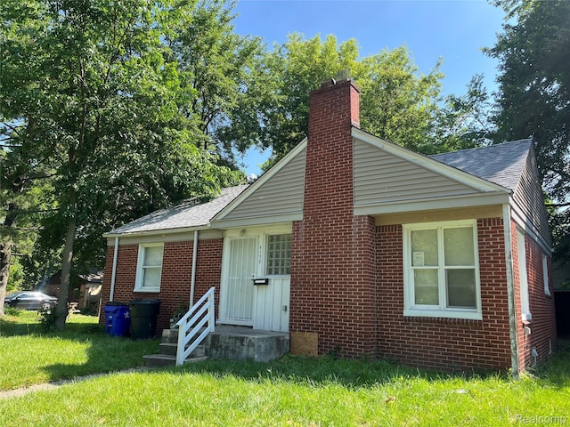 4150 Woodhall St, Detroit, MI 48224 - bungalow with a chimney, brick siding, a front lawn, and a shingled roof