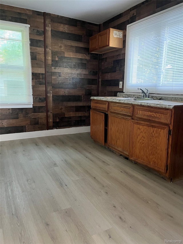 4150 Woodhall St, Detroit, MI 48224 - kitchen with wood walls, light wood-type flooring, brown cabinetry, light countertops, and a sink