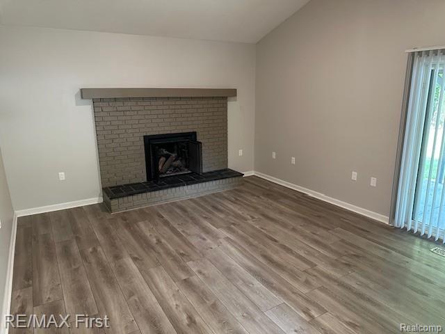 33315 Vista Way, Fraser, MI 48026 - unfurnished living room featuring wood finished floors, plenty of natural light, vaulted ceiling, baseboards, and a fireplace